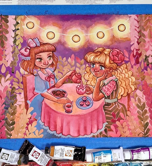 A finished watercolor and gouache painting by Luna Topaz featuring two girls having tea together under glowing lanterns. The girl on the left is pouring tea into the flowery cup that belongs to the girl on the right. The scene is surrounded by warm pink and purple foliage, with paint tubes visible below the artwork.
