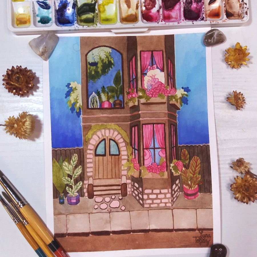 A work in progress of a watercolor painting by Luna Topaz titled "Spring Vibes" showing a tall building with arched windows filled with plants. The scene is bright and peaceful, surrounded by art supplies and dried flowers.
