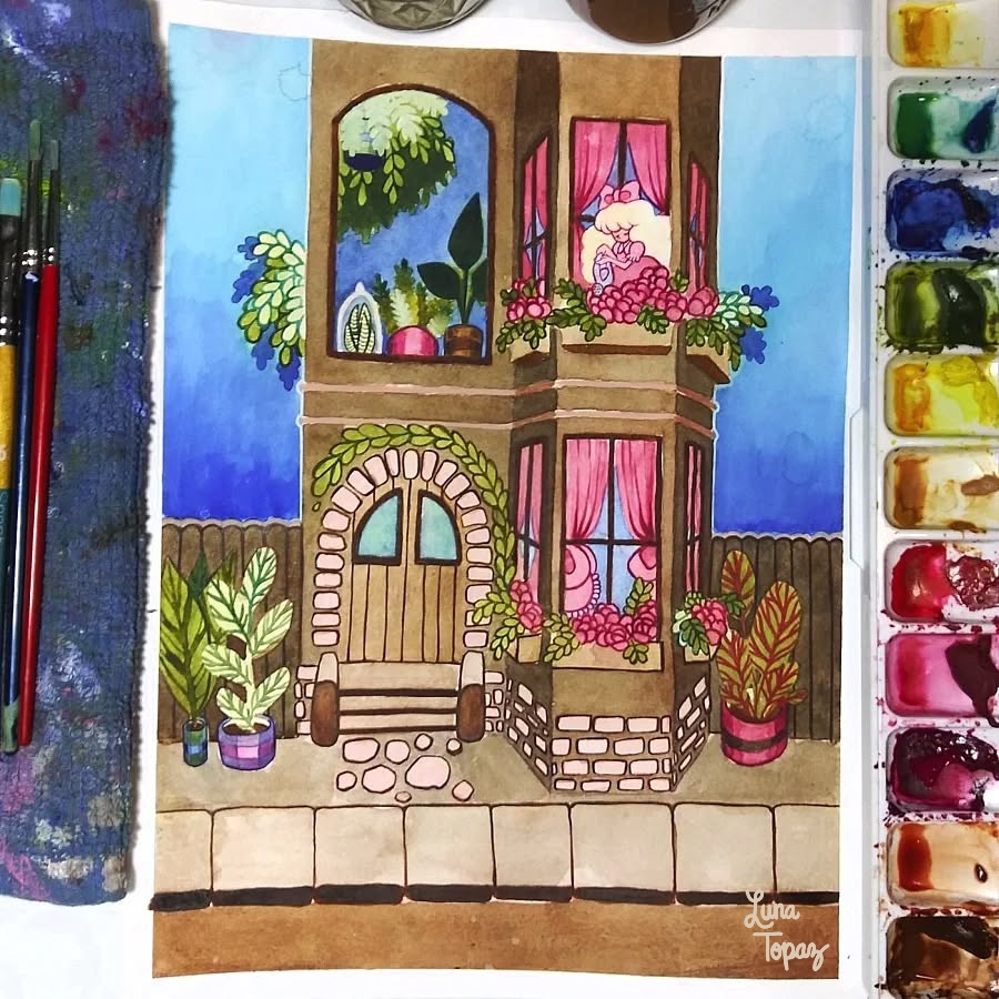 A finished watercolor painting by Luna Topaz titled "Spring Vibes" showing a tall building with arched windows filled with plants. The scene is bright and peaceful, surrounded by art supplies and dried flowers.
